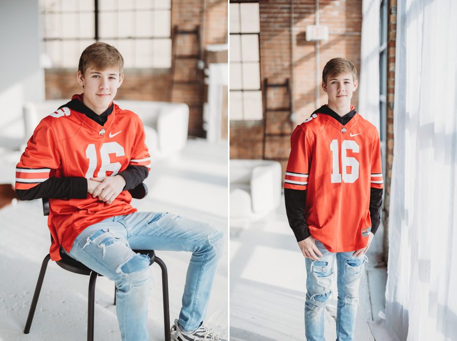 Alex wearing Ohio State jersey sitting on black chair with brick background